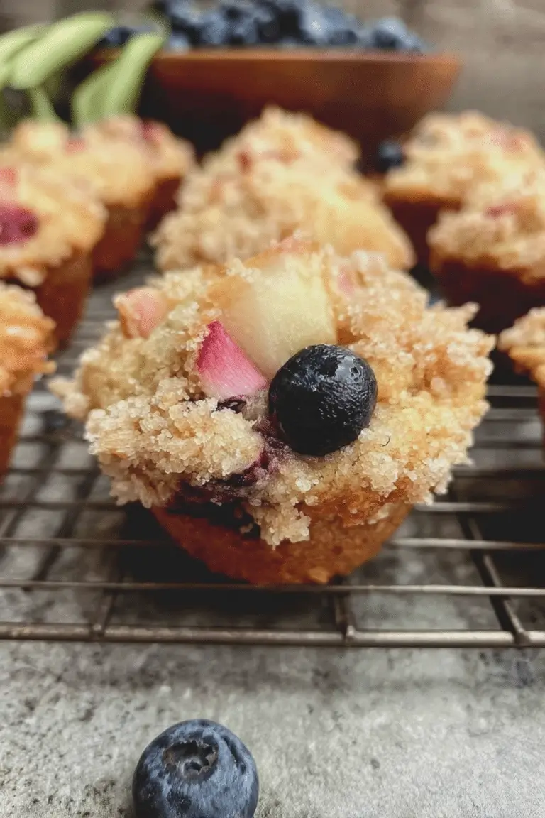 Blueberry rhubarb muffins topped with honey butter on a rustic wooden table.